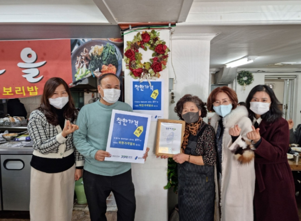 시 관계자가 신규 위촉된 착한가격업소 중 하나인 성산고을에 표찰을 전달하고 있다